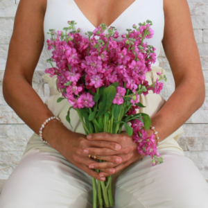 Mujer sentada con flores en la mano, disfrutando de salud mental.