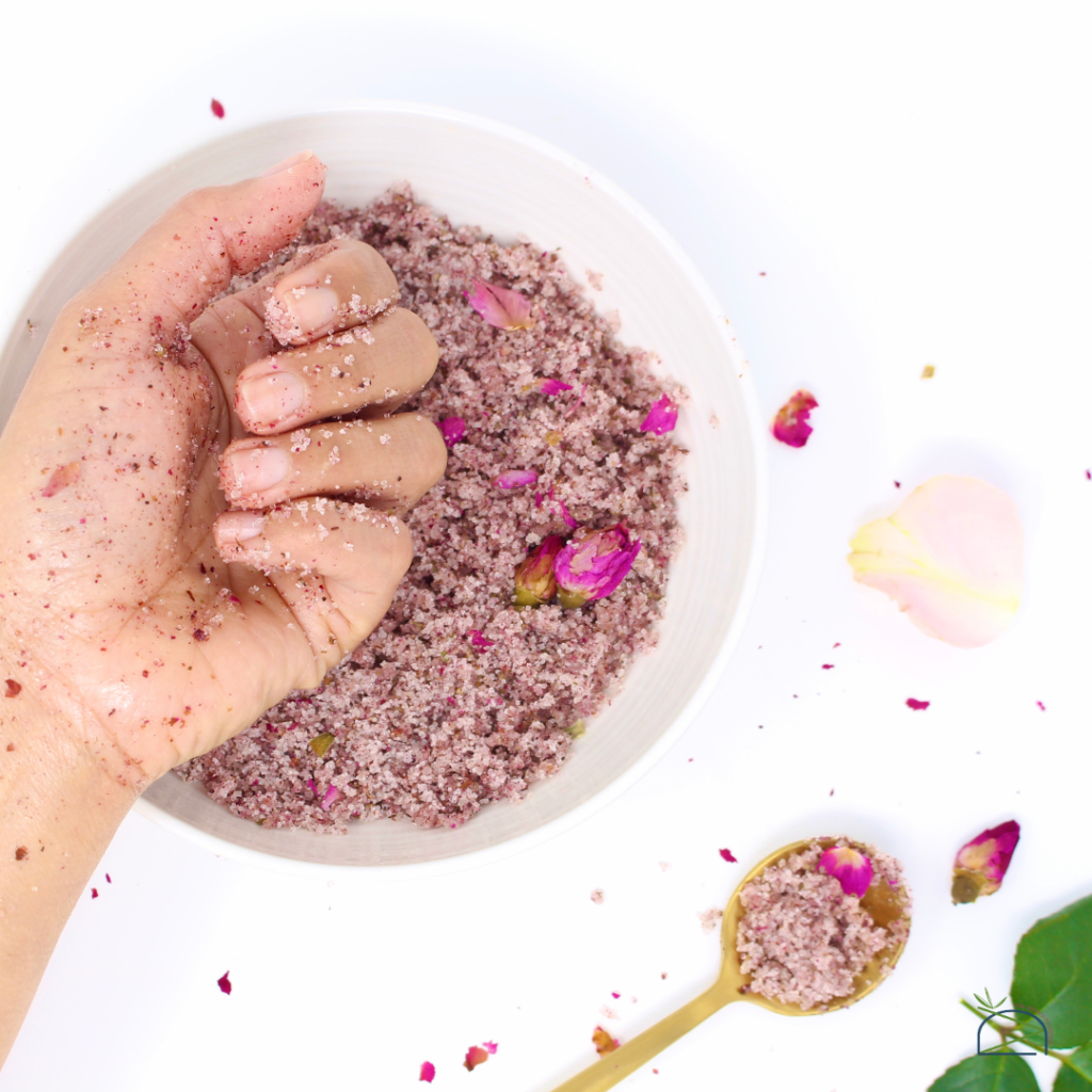 Mano de mujer con pétalos de rosa y azúcar saludable para la piel.